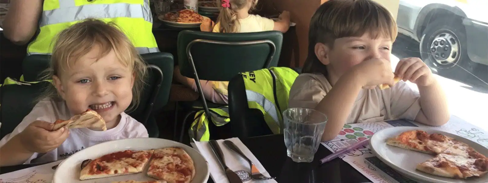 Kids eating pizza at a restaurant during a group outing.